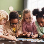 A diverse group of 4 children playing with a puzzle.